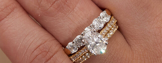 Oval cut diamond engagement ring stacked with gold pav&eacute; bands and five-stone diamond ring